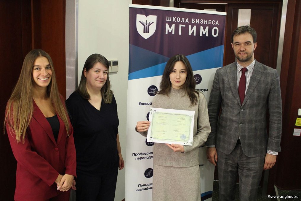 Слушательница программы по большим языковым моделям с удостоверением МГИМО у баннера Школы бизнеса